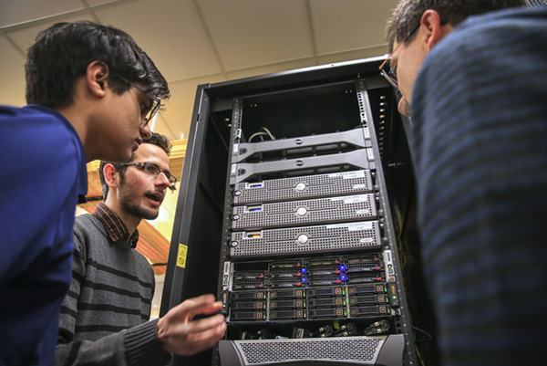 Students and professor examining mainframe computer.