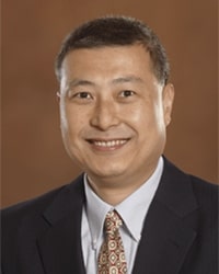 A man wearing a suit coat, collared shirt and tie poses for a headshot.