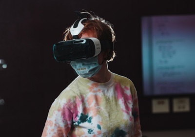A computer science student in a tie-dye shirt wearing a virtual reality headset.