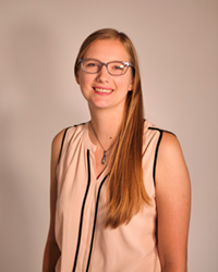 A woman wearing a white blouse and smiling at the camera.