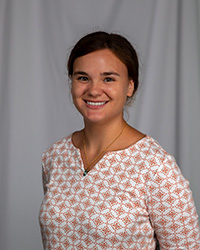 a woman with dark hair and a patterned blouse smiling at camera