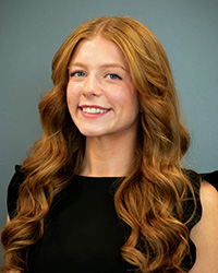 A woman with long wavy red hair smiling.