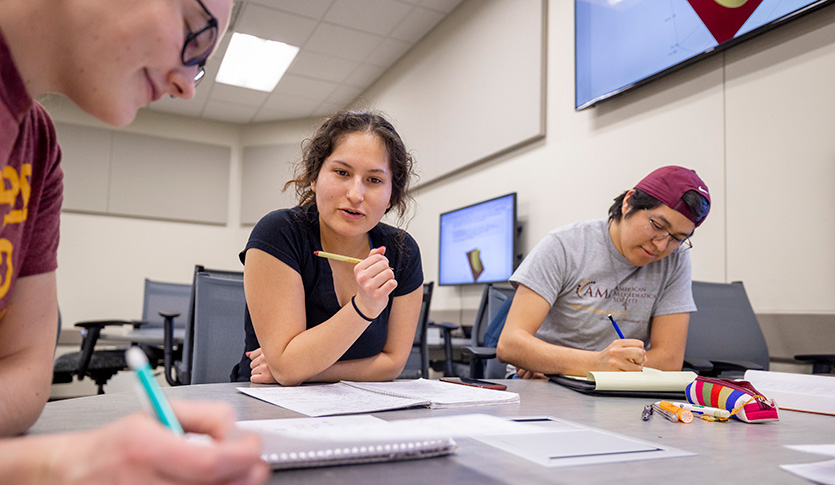 Three mathematics student collaborating on a problem in an active learning classroom.