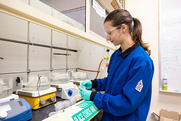 a person wearing protective glasses and gloves while working with samples in petri dishes