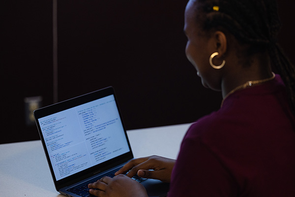 a woman typing on a laptop that is full of numerical data