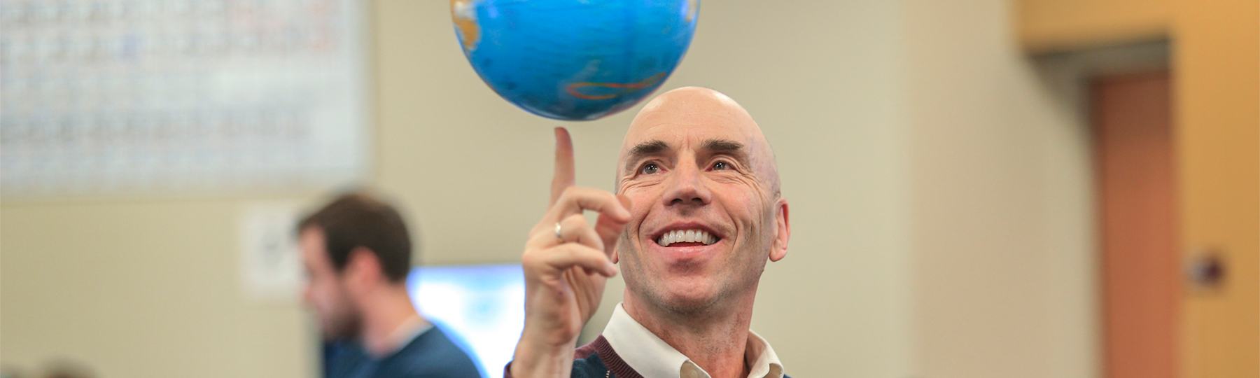 Geography faculty member, Mark Francek, spinning a globe on his finger.