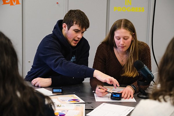 Students comparing and sharing data at a table in a classroom.