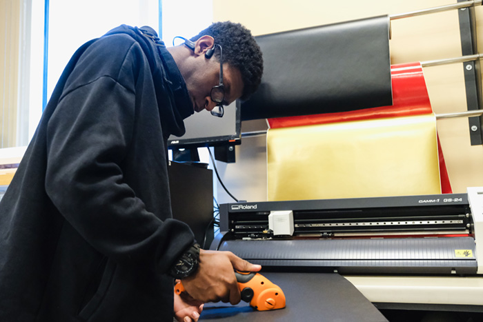 InSciTE student cutting materials in the STEM Center.