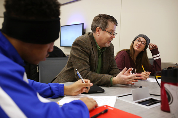 Two mathematics students having a classroom discussion with a faculty member.