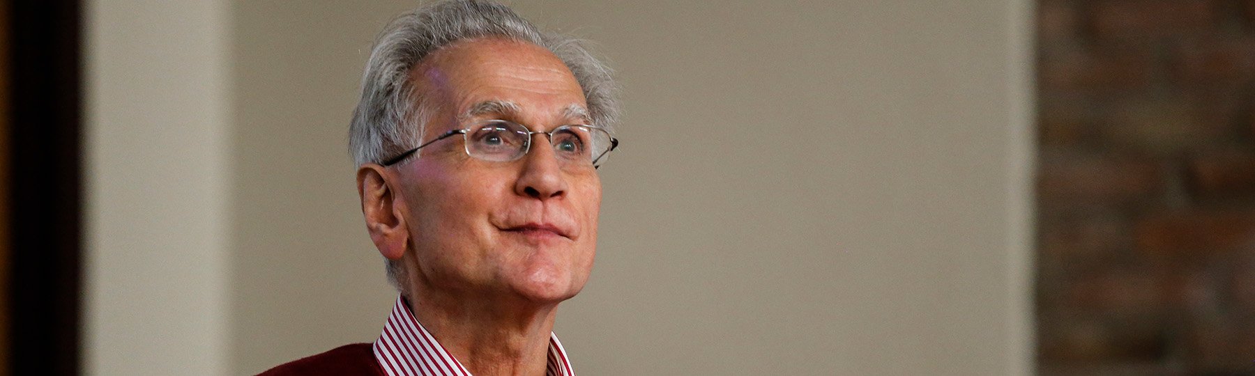 Man with gray hair and glasses standing in front of audience delivering a mathematics seminar.