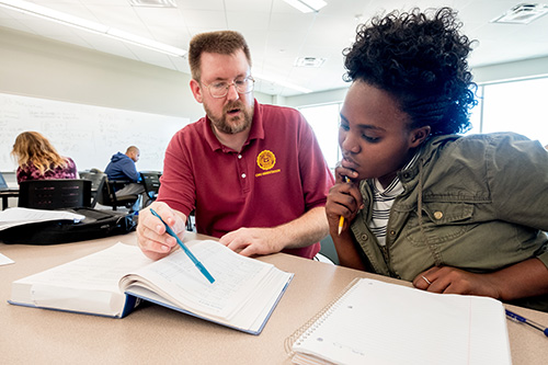 A tutor and a student examining a page in a textbook.