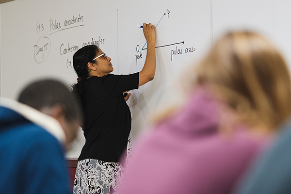 Meera Mainkar writing formula on whiteboard in front of classroom