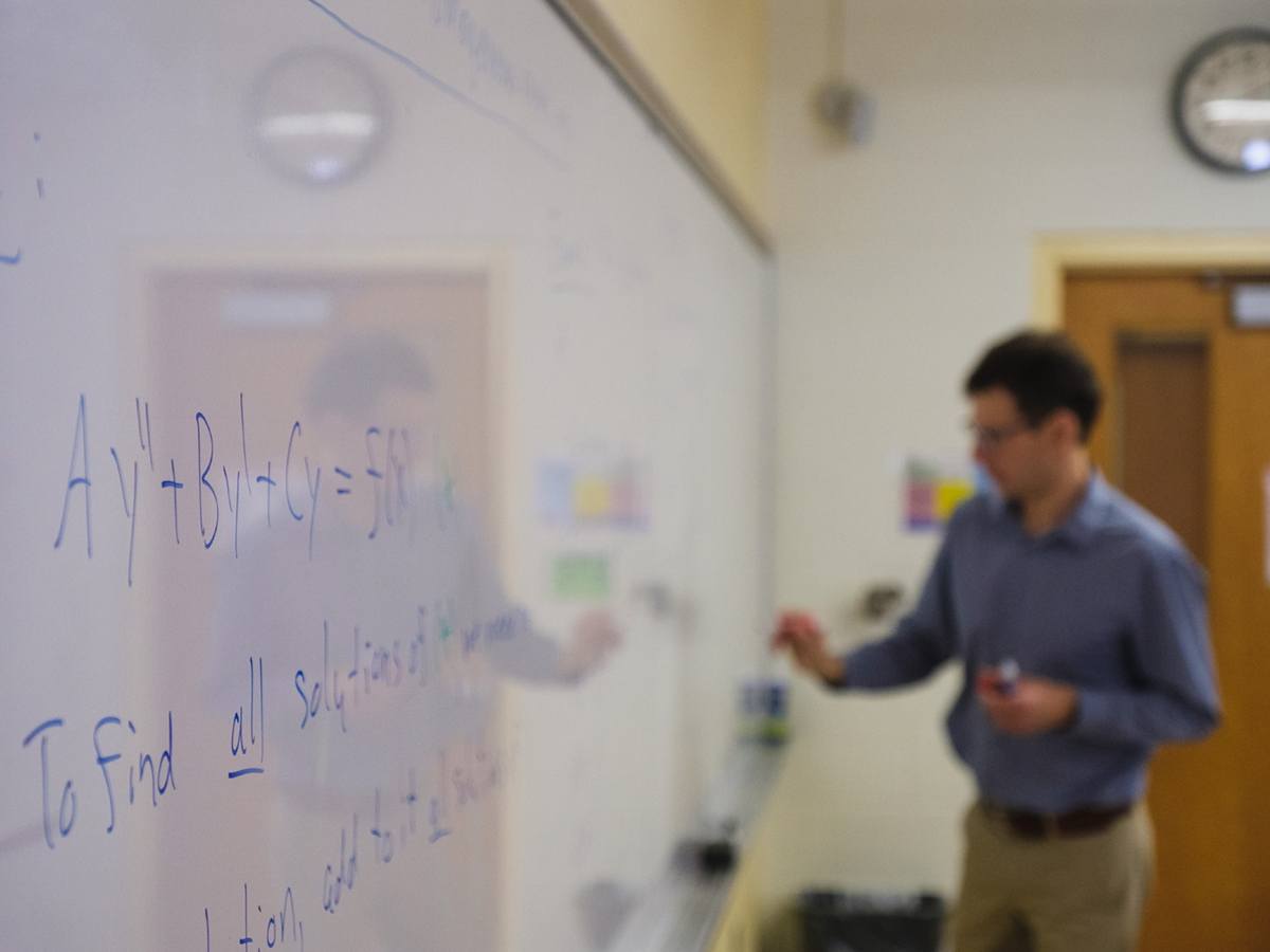Dmitry Zakharov writing formulas on a whiteboard in the classroom.