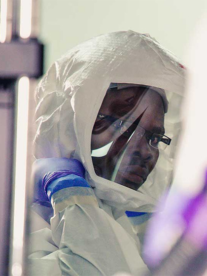 a man in a white protective suit in a secure lab area