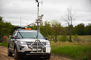The mobile mesonet (mobile weather monitoring vehicle) driving down a dirt road.
