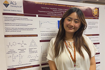 a woman with long hair standing in front of a research poster