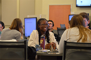 A woman in a white sweater sitting in a class.