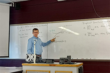 a man standing in front of a whiteboard full of mathematical equations