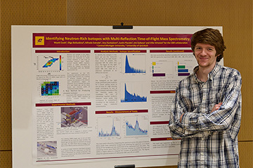 A man standing in front of a poster explaining his research