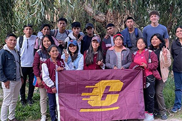 Itzel Marquez, Maxwell Hornak, and a group of individuals in Copacabana Bolivia holding a CMU flag.