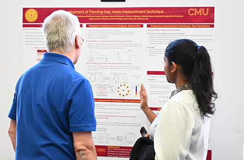 Physics faculty member and a graduate student examining the data on her research poster