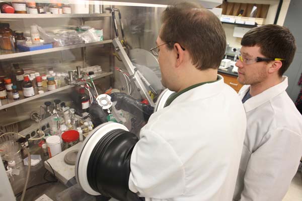 Science of Advanced Materials Students examining samples under a hood.