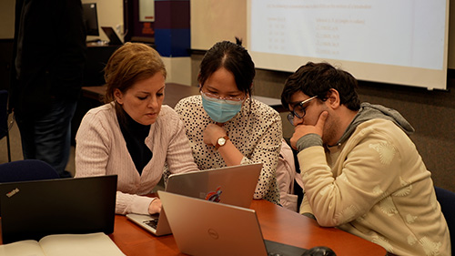 Three students examining data on a laptop.