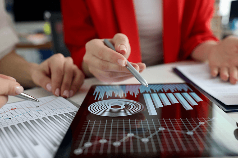 Two people look at statistical graphs on a tablet screen.