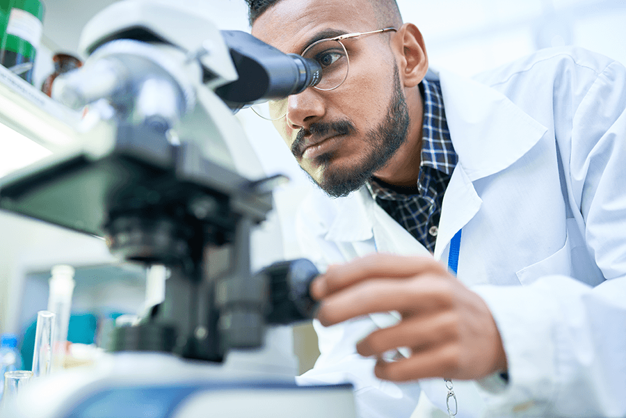 A researcher looks through a microscope at a slide.