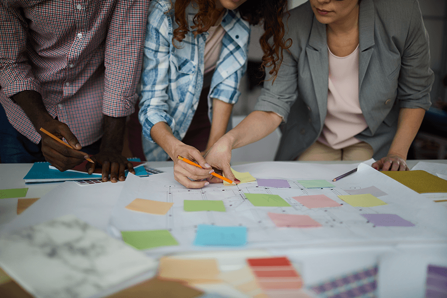 Three people work on a map covered with sticky notes.