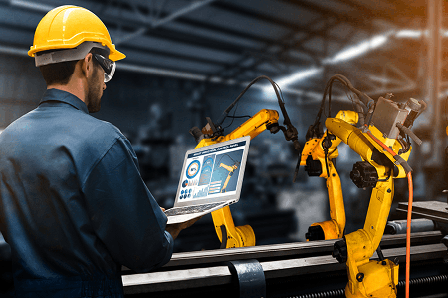 An engineer controls machine arms through a laptop.