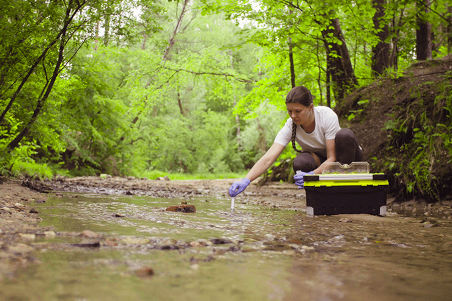 A student collects water samples from a river.