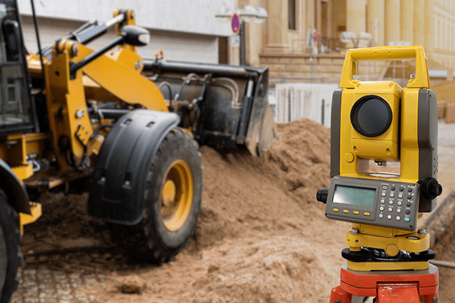 Survey equipment set up in front of construction equipment.