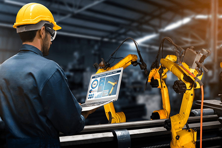 An engineer controls machine arms on an assembly line.