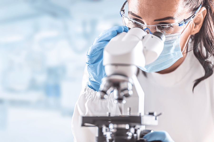 A researcher looks through a microscope.