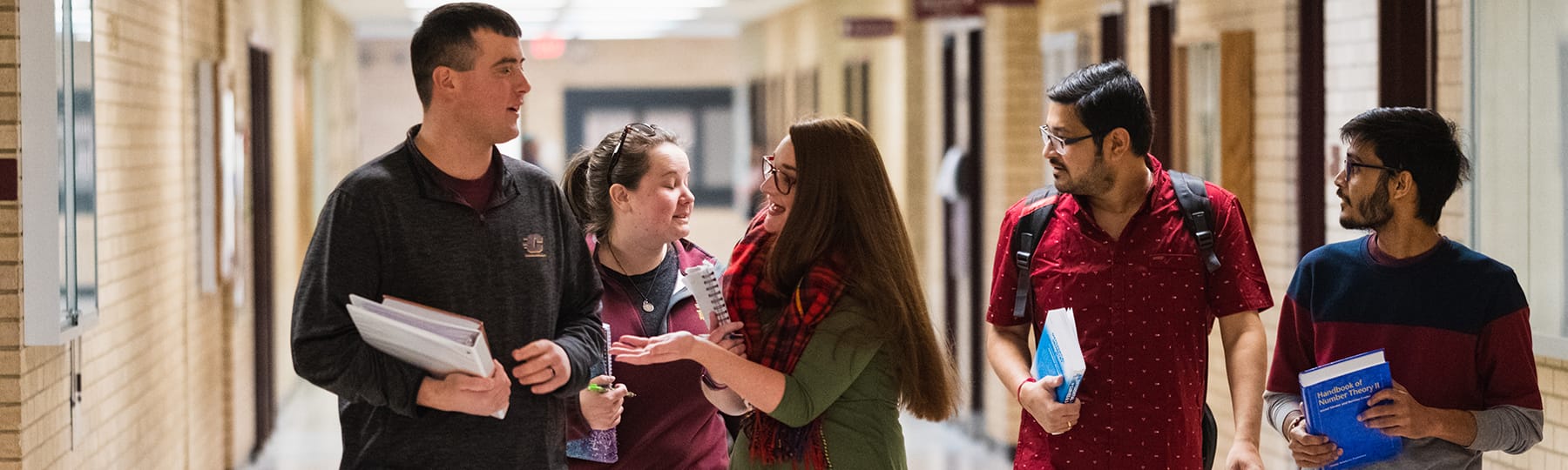 A group of mathematic students walk down the hallway on campus.