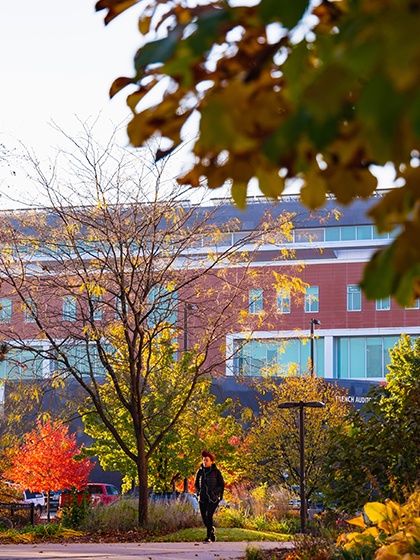 A student walking on campus during fall.