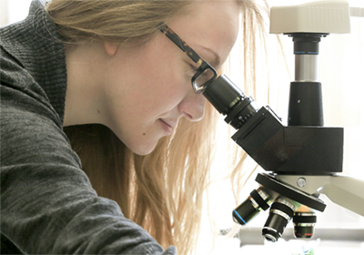Student examining samples under microscope.