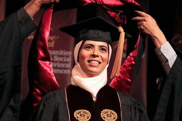 A student receives her hood at commencement.