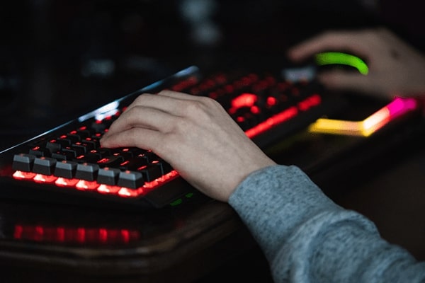 Student typing on a lit up computer keyboard.