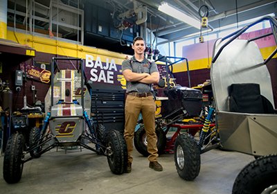 Baja student standing next to the Baja vehicle.