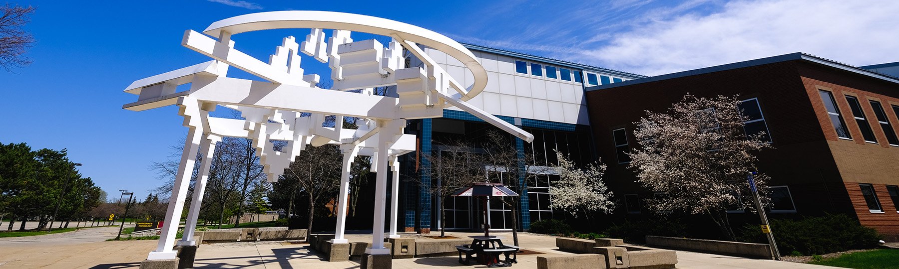 A white art structure outside a building.
