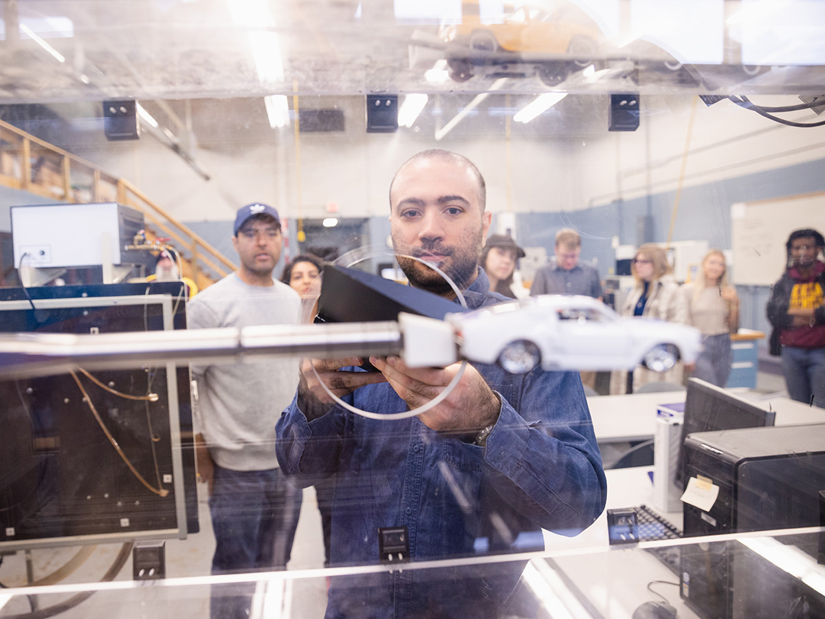 A man holding positioning a model car in an aerodynamics measuring class case.