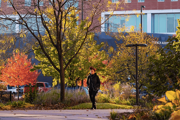 Student walking in front of French Auditorium in the Fall.