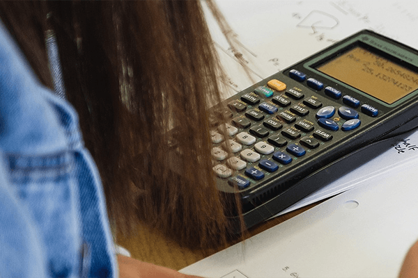 Math student using graphic calculator to solve math problems.