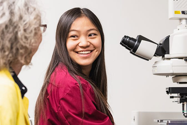 A student and professor near a microscope.