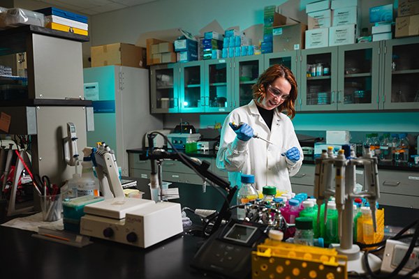 Female student in a lab coat preparing samples in a medical lab.