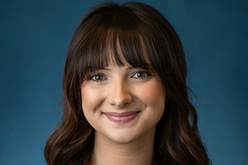A headshot photo of Bailey Blaisdell against a blue backdrop.