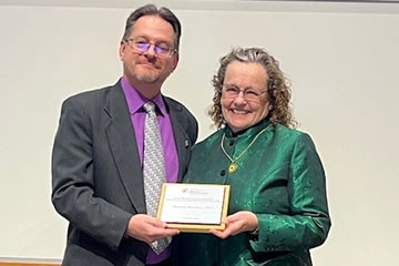 Dean Tom Masterson poses with Marcia Mackey holding a College of Health Professions Community Partnership Award plaque.
