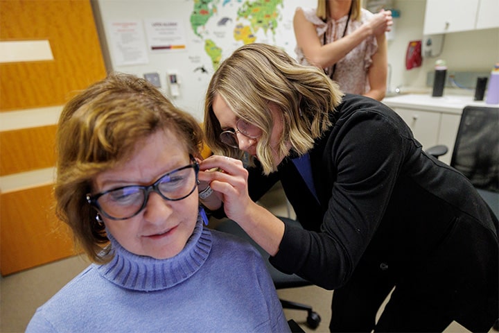 An audiology student examines a patient's ear.